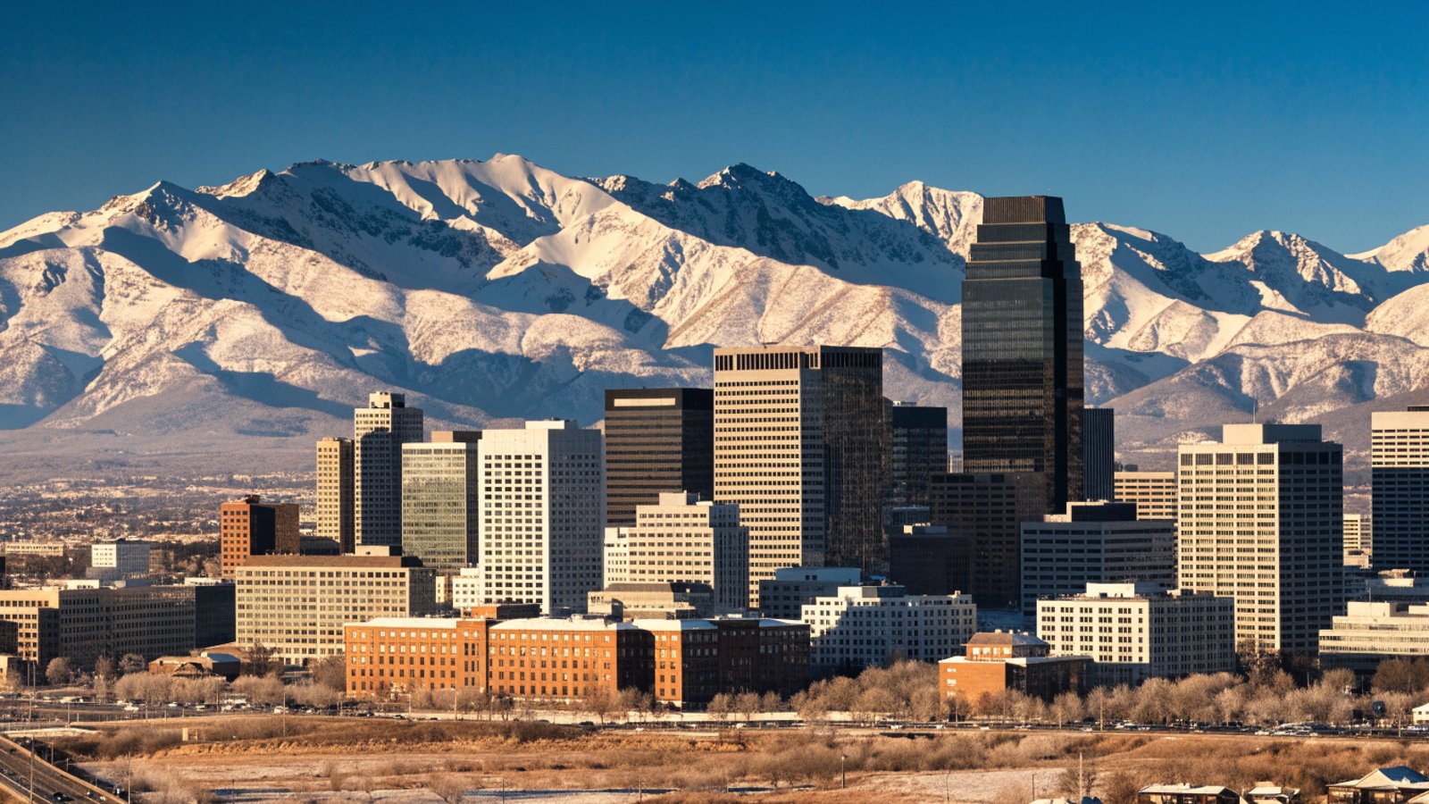 Denver skyline with snow-covered mountains on a clear late-winter morning.